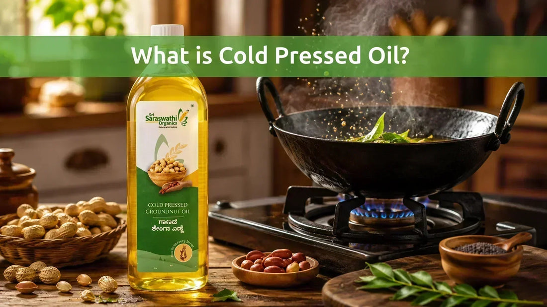 Sri Saraswathi Organics cold pressed groundnut oil bottle in a kitchen with a traditional iron kadai tempering mustard seeds and curry leaves